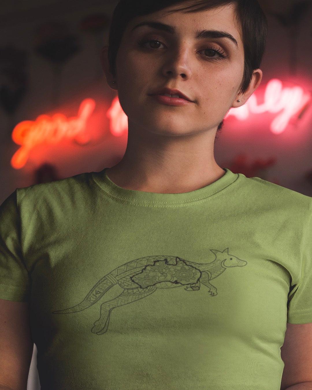 RUGBYNOMAD wasabi color organic cotton women's streetwear t shirt on a dark haired female model standing with a red neon sign behind her with a gray australia wallaby artistic tribal design