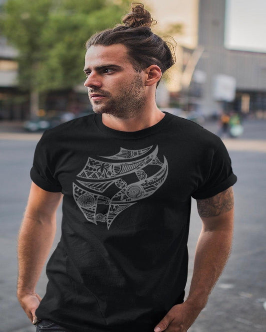 RUGBYNOMAD black organic cotton heavyweight streetwear t shirt with a fiji tribal artistic design on a male model with dark hair in a ponytail with hands in his pockets standing on the street looking to his right